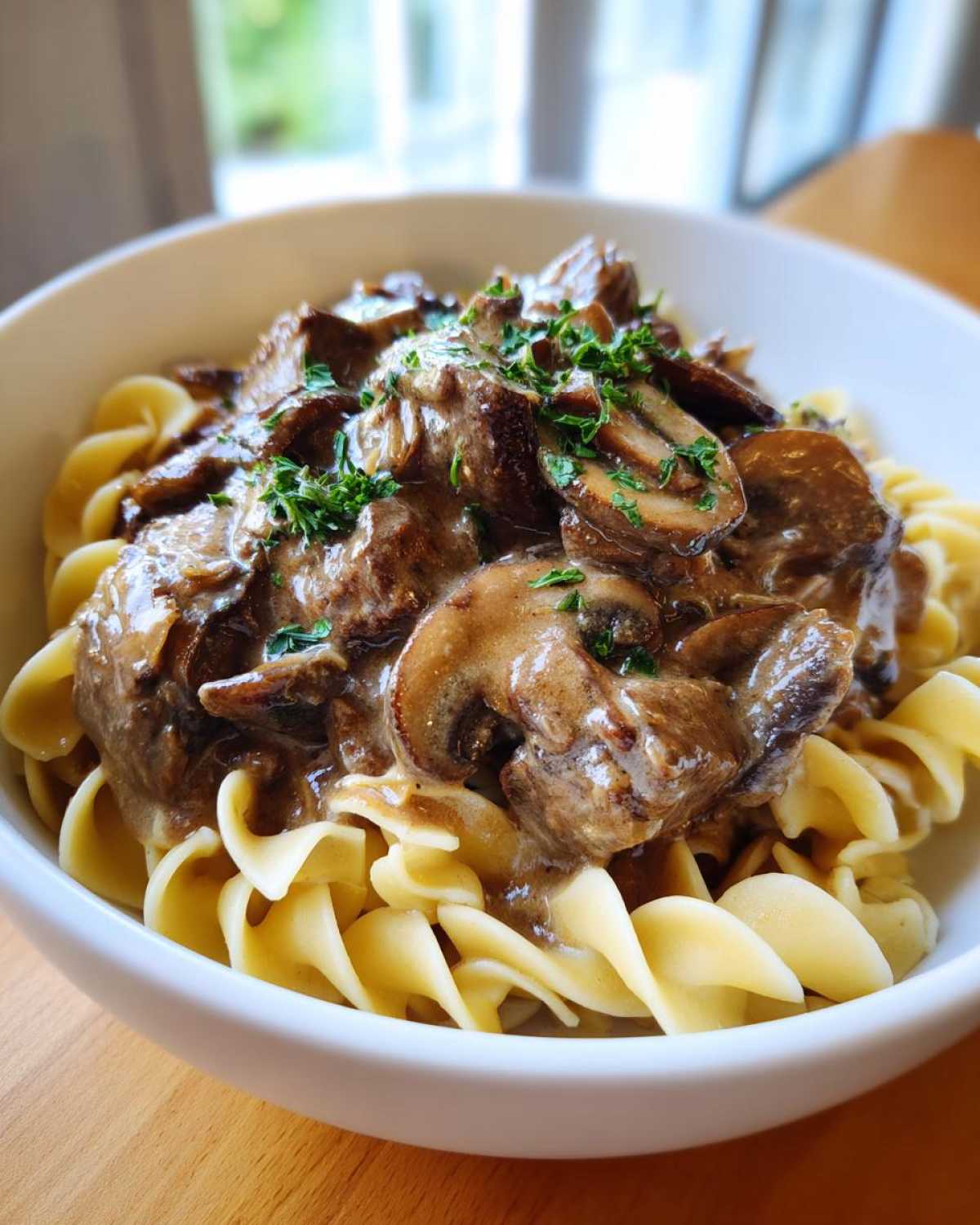 A close-up of Instant Pot Beef Stroganoff with Mushrooms served over egg noodles in a white bowl.