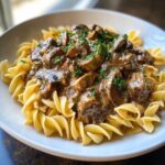 Close-up of creamy Instant Pot Beef Stroganoff with Mushrooms served over egg noodles, garnished with parsley.