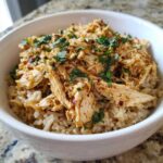 Close-up of Instant Pot Chicken Burrito Bowls featuring seasoned shredded chicken over brown rice, topped with fresh cilantro.