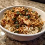 Close-up of Instant Pot Chicken Burrito Bowls with brown rice topped with shredded seasoned chicken and cilantro.