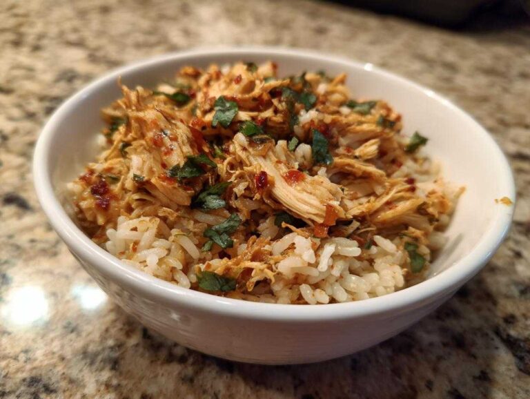 Close-up of Instant Pot Chicken Burrito Bowls with brown rice topped with shredded seasoned chicken and cilantro.