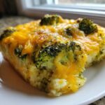 Close-up of a serving of Keto Cheesy Broccoli Casserole topped with melted cheddar cheese and visible broccoli florets.