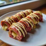 Close-up of Keto Italian Sub Roll-Ups showing layers of deli meat and melted cheese oozing out.
