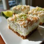 A square slice of No-Bake Coconut Lime Bars with a graham cracker crust, topped with toasted coconut and lime zest.
