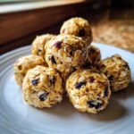 A stack of No-Bake Lemon Blueberry Energy Bites made with oats and dried fruit on a white plate.