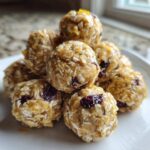 A stack of No-Bake Lemon Blueberry Energy Bites made with oats, coconut, and dried fruit on a white plate.