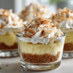 Close-up of individual No-Bake Lemon Coconut Cream Pie Cups topped with whipped cream and toasted coconut.