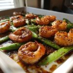 Close-up of glistening One-Pan Honey Garlic Shrimp and Snow Peas coated in a dark, savory sauce.