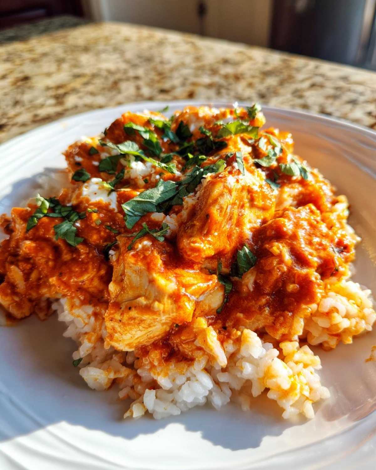 A serving of One-Pot Creamy Tomato Basil Chicken and Rice topped with fresh basil on a white plate.