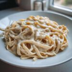 Close-up of fettuccine pasta generously coated in rich Vegan Creamy Cashew Alfredo Sauce and black pepper.