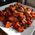 Close-up of Sheet Pan Harissa Chicken with Sweet Potatoes, garnished with fresh parsley.