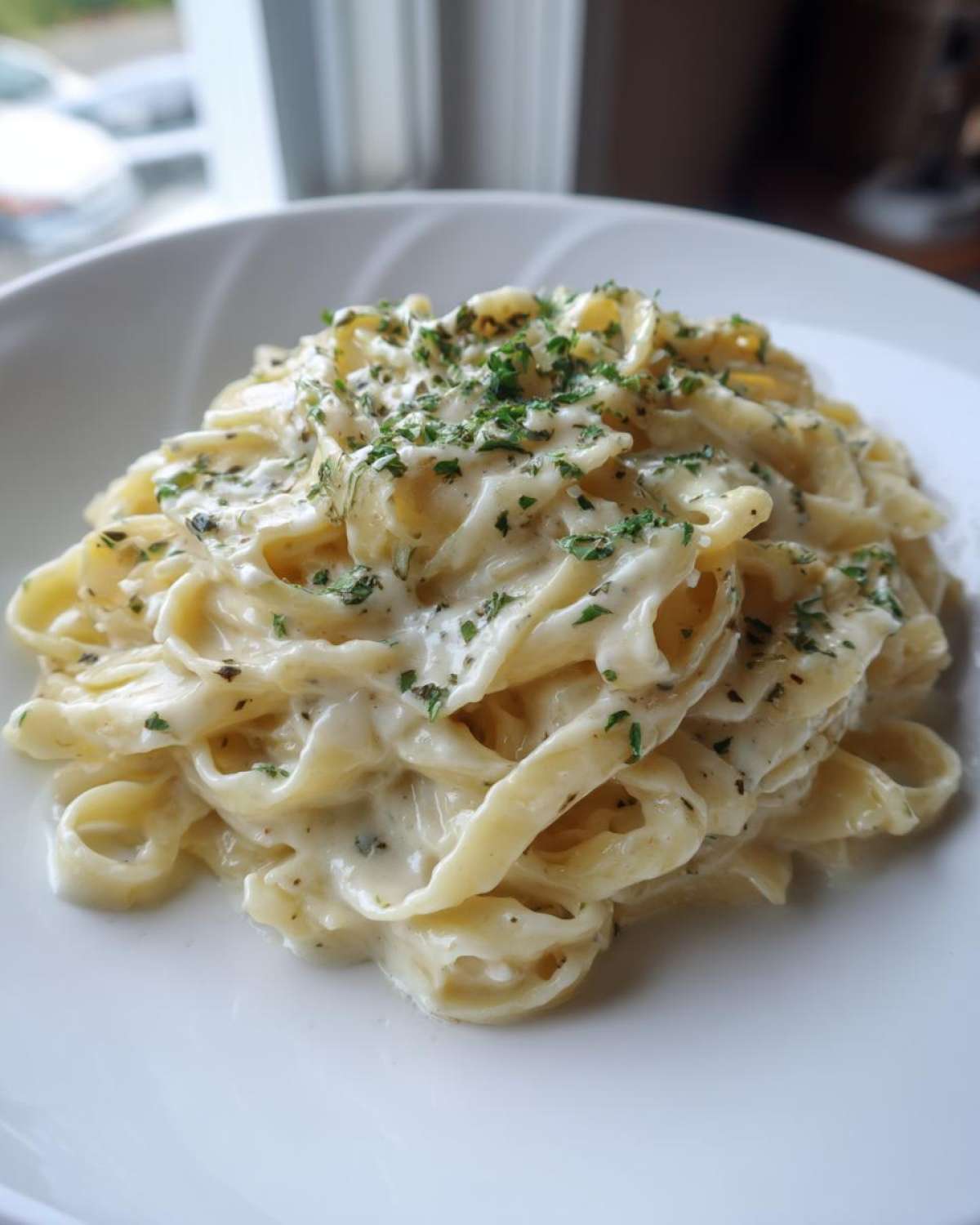 A close-up of fettuccine pasta coated in Vegan Creamy Cashew Alfredo Sauce and topped with fresh parsley.