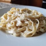 Close-up of fettuccine pasta generously coated in Vegan Creamy Cashew Alfredo Sauce on a white plate.