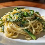 Close-up of creamy Vegan Lemon Asparagus Pasta with bright green asparagus spears and pea shoots.