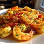 A close-up of juicy Air Fryer Crispy Garlic Butter Shrimp coated in melted butter and fresh parsley, served on a white plate.