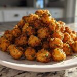 A mound of golden brown Air Fryer Crispy Garlic Herb Chickpeas seasoned with visible green herbs on a white plate.