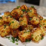 A mound of golden brown Air Fryer Crispy Garlic Parmesan Potato Cubes garnished with parsley and cheese.