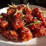 A plate of glossy, red-glazed Air Fryer Crispy Korean Chicken Bites sprinkled with sesame seeds and green onions.