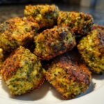 A pile of golden brown, crispy Air Fryer Crispy Parmesan Broccoli Tots stacked on a white plate.