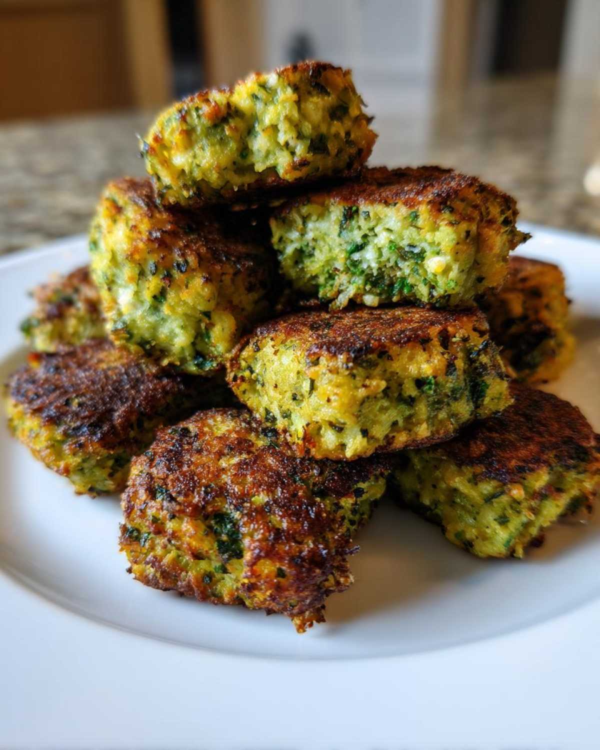 A stack of golden-brown Air Fryer Crispy Parmesan Broccoli Tots piled on a white plate.