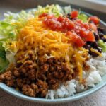 A close-up of a fully assembled Air Fryer Crispy Turkey Taco Bowl with rice, seasoned ground turkey, lettuce, cheese, and salsa.