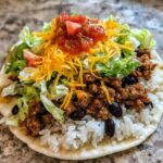 Close-up of an assembled Air Fryer Crispy Turkey Taco Bowls base with rice, seasoned ground turkey, black beans, lettuce, cheese, and salsa.
