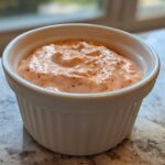 A close-up of the creamy, pinkish Copycat Classic Burger Spread Sauce served in a small white ramekin.