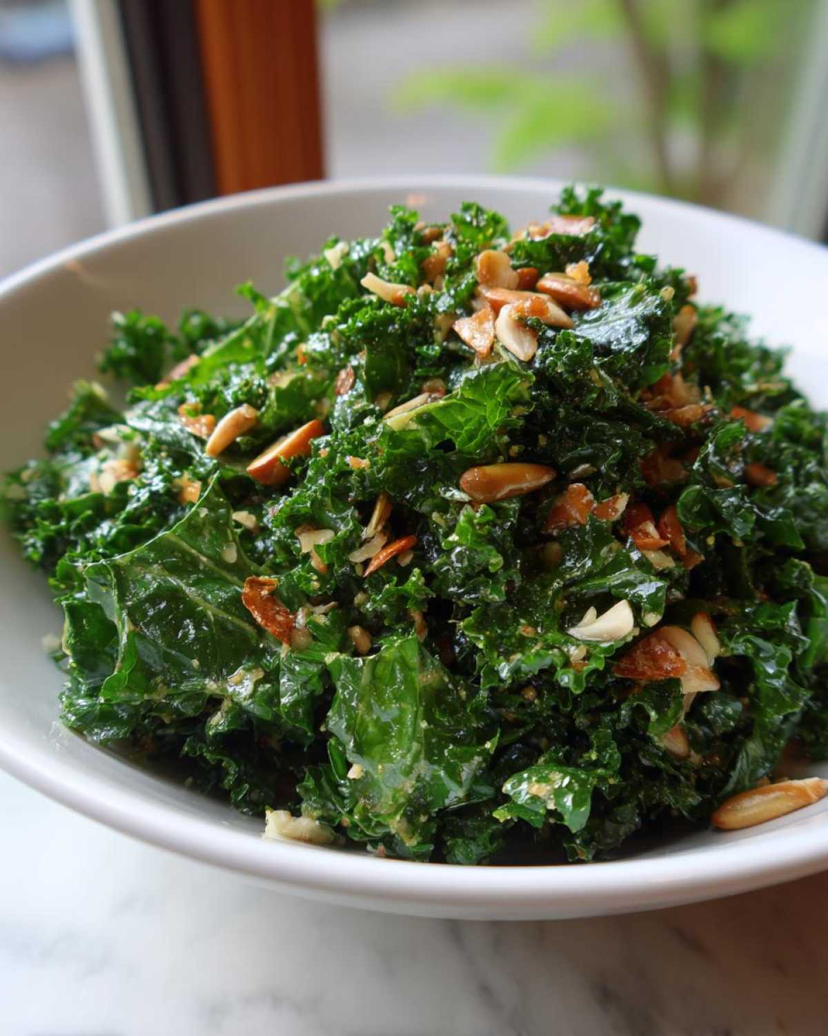 A vibrant bowl of Copycat Kale Crunch Salad coated in dressing and topped with toasted sliced almonds.