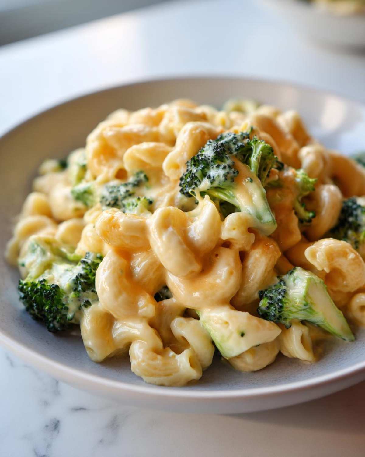 Close-up of creamy Copycat Café Broccoli Cheddar Mac served in a light gray bowl.