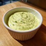 Close-up of creamy, pale green Easy 5-Minute Salsa Verde Yogurt Dip swirled in a white ramekin.