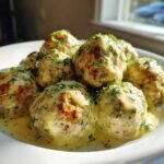 A plate of Easy Creamy Greek Chicken Meatballs covered in a light yellow sauce and fresh dill.