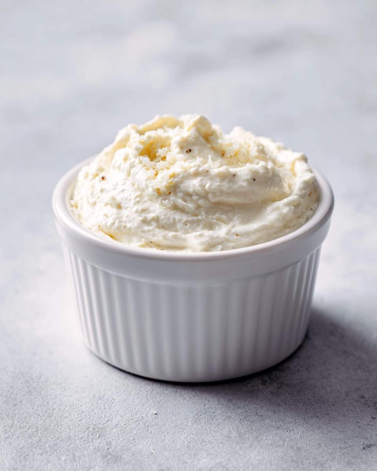 A close-up of thick, creamy Easy Greek Yogurt Caesar Dressing served in a small white fluted ramekin.