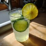 Close-up of a glass containing Easy Iced Cucumber Lime Agua Fresca with cucumber slices and a lime wheel garnish.
