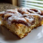 Close-up of a single square serving of Easy Sheet Pan Cinnamon Roll Pancake Bake topped with white icing.