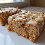 Two slices of Gluten-Free Carrot Cake Baked Oats topped with a creamy vanilla glaze, served on a white plate.