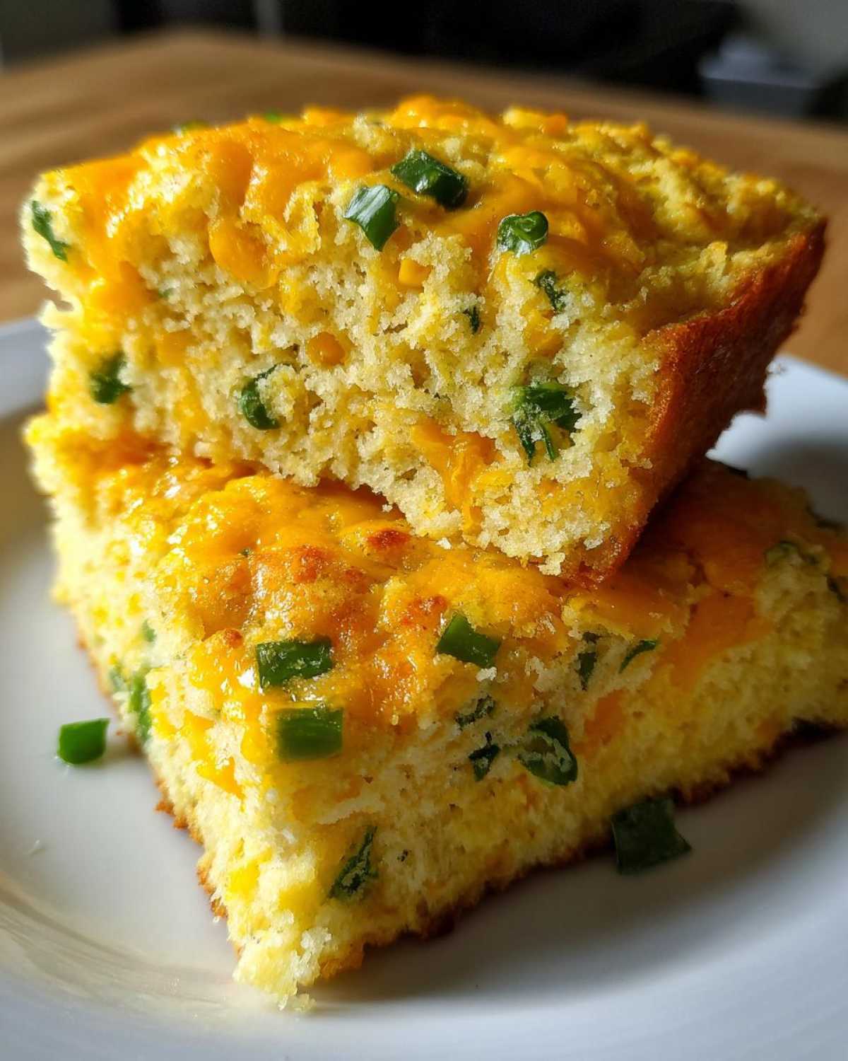 Close-up of two stacked slices of moist Gluten-Free Cheddar Jalapeno Cornbread topped with melted cheese and green onions.
