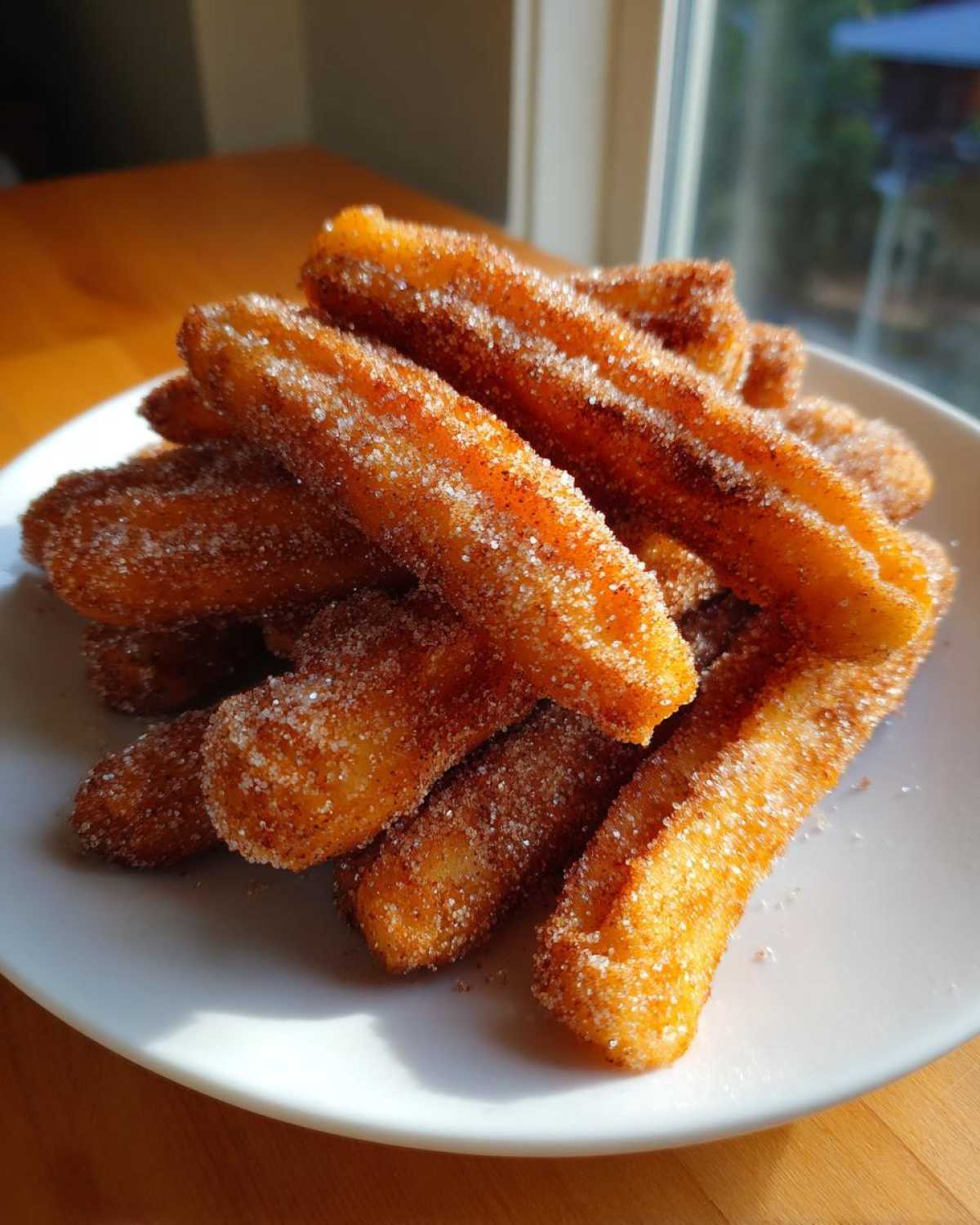 A pile of crispy, golden Gluten-Free Cinnamon Sugar Waffle Sticks coated heavily in sparkling sugar.