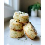 A stack of three Gluten-Free Lemon Thyme Shortbread Cookies, topped with sugar and fresh thyme.