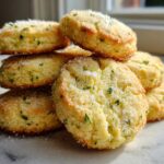 A stack of golden Gluten-Free Lemon Thyme Shortbread Cookies topped with coarse sugar and flecks of green thyme.