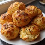 A stack of golden baked High-Protein Cottage Cheese Bagel Bites topped with everything bagel seasoning on a white plate.