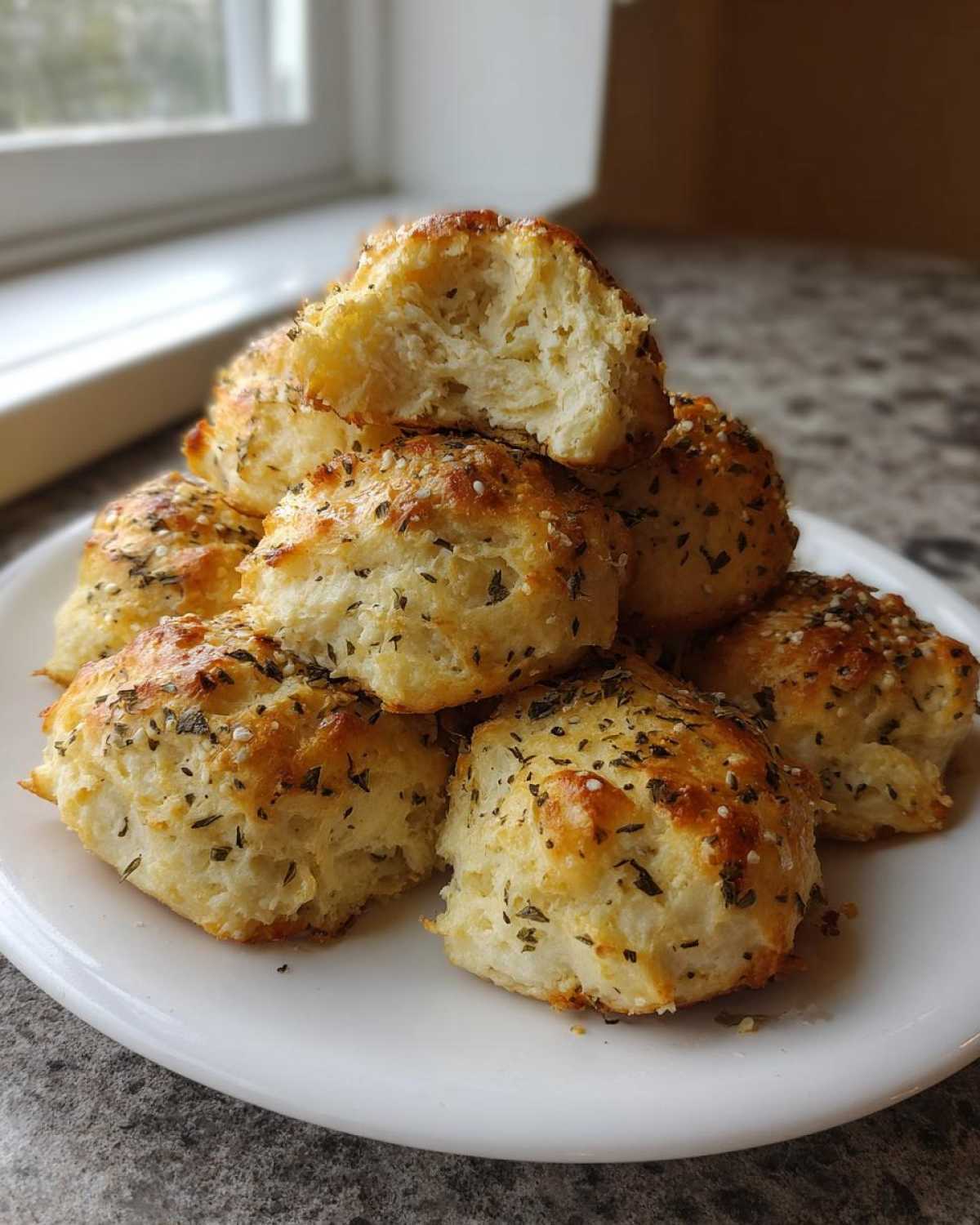 A stack of golden-brown High-Protein Cottage Cheese Bagel Bites topped with everything bagel seasoning on a white plate.