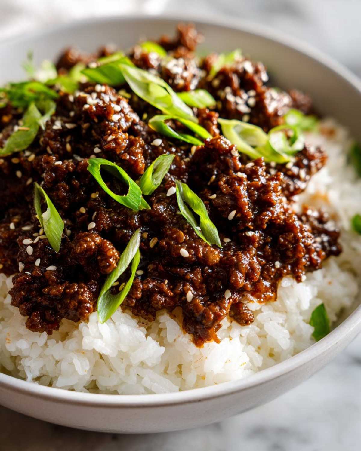 Close-up of Instant Pot Korean Beef and Rice Bowls topped with green onions and sesame seeds.