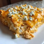 A generous serving of Keto Creamy Buffalo Chicken Casserole topped with melted cheddar and blue cheese crumbles.