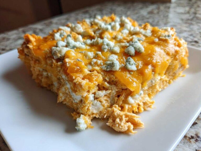 A generous serving of Keto Creamy Buffalo Chicken Casserole topped with melted cheddar and blue cheese crumbles.