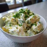 A white bowl filled with Keto Creamy Herb Deviled Egg Salad, topped generously with fresh chopped chives.
