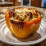 A single, bright yellow Keto Creamy Italian Sausage Stuffed Pepper topped with melted and browned cheese.