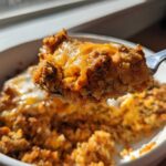 Close-up of a spoonful of Keto Creamy Taco Skillet with Cauliflower Rice, showing ground meat, cheese, and rice texture.