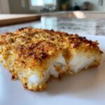 A close-up shot showing the flaky white interior and golden, crispy Keto Crispy Parmesan Crusted Cod topping.