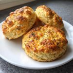 Close-up of three golden-brown Keto Everything Bagel Cloud Bread puffs topped with poppy seeds on a white plate.