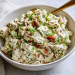 A creamy bowl of Keto Lemon Herb Chicken Salad mixed with fresh herbs and topped with whole almonds.